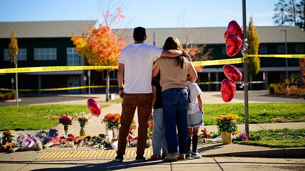 Community members grieve at the site of a makeshift memorial in front of Silver Rail Elementary School in Bend, Oregon