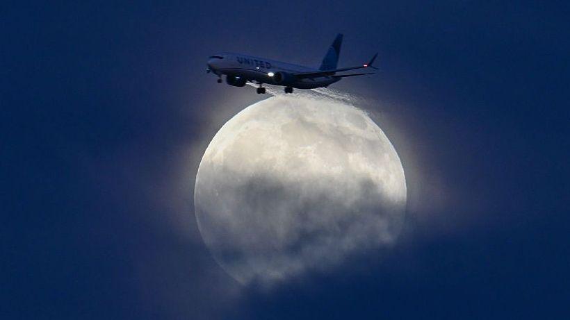 A large, glowing white moon above a sky with flapping clouds
